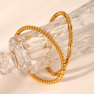 Macro detail of 18K gold plated stainless steel bead bracelet on glass pedestal