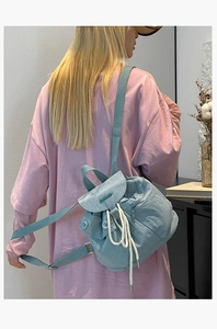 Light blue drawstring mini backpack with front pockets shown on model back