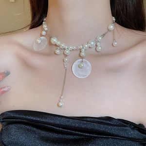 Detail of elegant pearl and shell tassel necklace on model's neck with silver chain