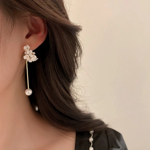 Eleganti orecchini floreali con perle bianche e strass indossati da una modella in profilo