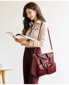Detail of burgundy PU leather tote bag with striped handles and golden hardware accents