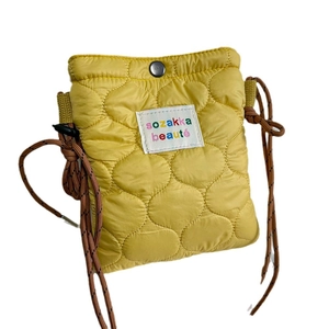Quilted yellow nylon crossbody bag with chic diamond stitching and woven strap