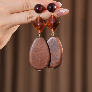 Detail of three-tier geometric earrings with resin beads and wood texture drops