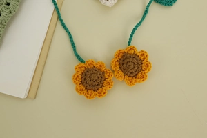 Close-up detail of handmade crochet sunflower pendant with green braided cotton cord