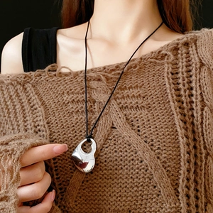 Detailed view of irregular silver double heart pendant on a minimalist black cord necklace
