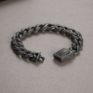 Detail view of retro steel curb chain bracelet with textured pattern and box clasp