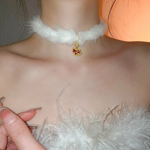 Close-up of plush white choker with a red enamel rocking horse pendant and gold engraving