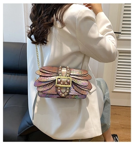 Detailed shot of rainbow snakeskin texture with gold buckle and pearl accents on the handbag