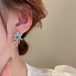 Elegant star earrings with light blue crystals and white cubic zirconia on a model