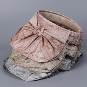 Detail of stacked sun visors with bowknot decoration and pleated fabric texture