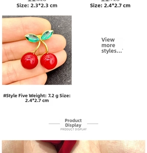 Detailed view of red cherry brooch with green gemstone leaves and gold finish