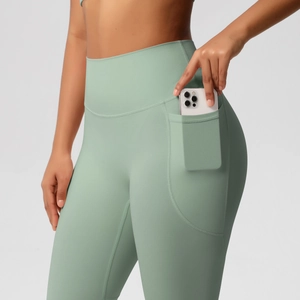 Detail of high-waisted yoga pants in sage green with a practical side phone pocket