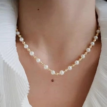 Detail view of natural white pearl necklace with gold beads on female neck