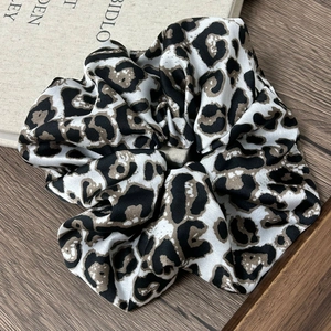 Detailed view of leopard print scrunchie on vintage books with silk texture
