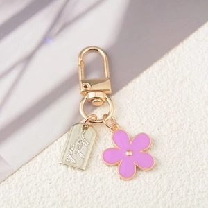 Detailed close-up of handmade pink floral keychain with a gold plated metal charm