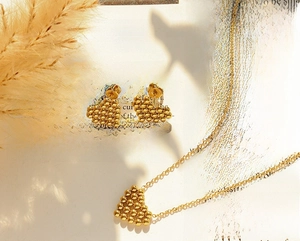 Polished gold heart earrings and necklace set displayed on a vintage book page