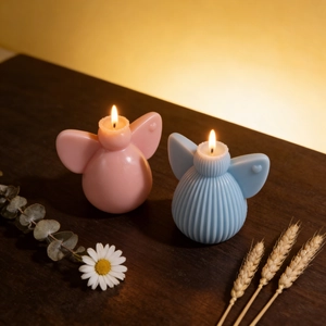 Detailed view of pink smooth and blue striped angel wing candles on a wooden table