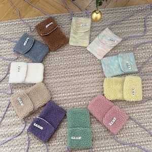 Flat lay of colorful plush crossbody phone bags in various shades with purple lanyards
