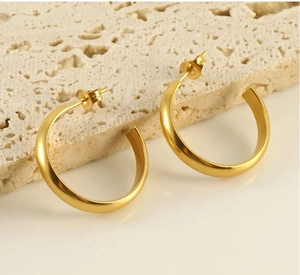 Detailed view of minimalist gold C-shaped hoop earrings on natural stone texture