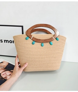Detail of woven tote bag with wooden handles and decorative turquoise stone accents