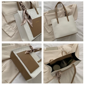 Detail of elegant two-tone tote bag with woven texture, silk scarf and front pocket
