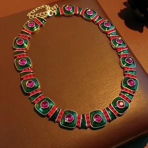 Detail of vintage necklace with green enamel tiles, red beads and pink stones on leather