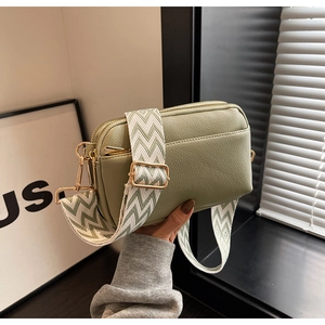 Detail of light green PU leather bag with geometric wave strap and golden hardware