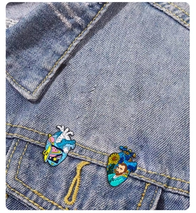 Detailed view of Van Gogh and outer space themed heart enamel pins on denim jacket pocket