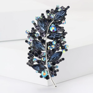 Macro shot of silver leaf brooch featuring deep blue rhinestones and iridescent crystals