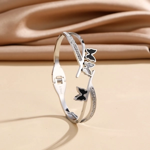 Detail of silver stainless steel wide butterfly bangle with black and white enamel wings