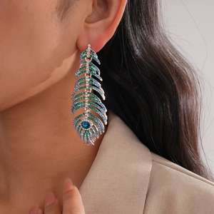 Détail de boucles d'oreilles bohèmes avec cristaux bleus et verts sur base argentée
