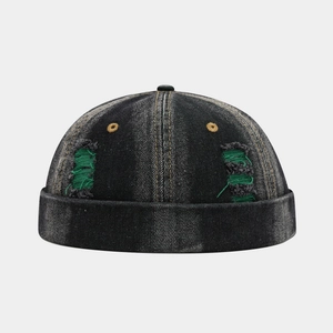 Detail of black denim docker hat with green distressed holes and yellow eyelets