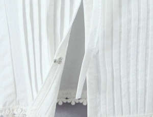 Détails d'agrafes métalliques invisibles et de plis verticaux sur vêtement en dentelle