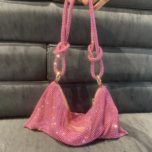 Detail shot of pink rhinestone shoulder bag showing knots on strap and metal mesh texture