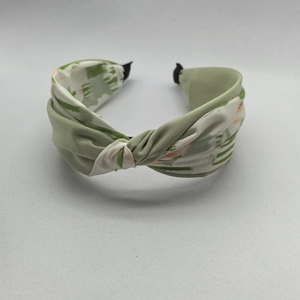 Elegant green and white knotted headband with abstract patterns on a white background