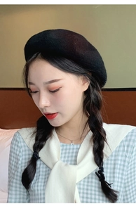 Chic black wool beret paired with a plaid shirt and scarf on a model close-up