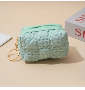 Detail of light blue waffle texture mini pouch with gold metal ring hook and zip closure