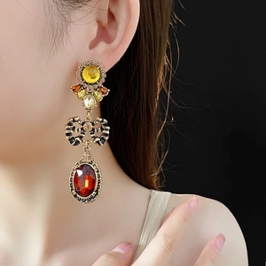 Detailed view of vintage gold earrings with red oval gemstones on a model's ear