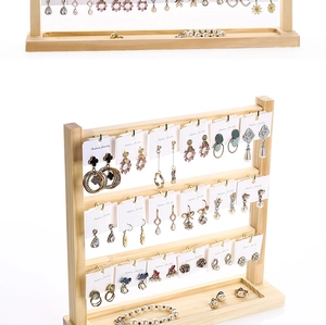 Macro detail of three-tier solid wood earring organizer with grooved base tray for jewelry