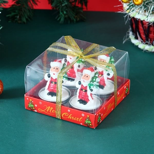 Dettaglio di quattro candele a forma di Babbo Natale in confezione regalo con nastro d'oro