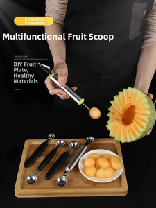 Close-up of stainless steel melon baller and carving knife making fruit balls