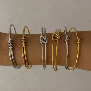 Détail de bracelets nœuds minimalistes en or et argent portés par un mannequin