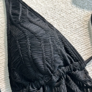 Detailaufnahme eines schwarzen Bikini-Oberteils mit gewellter Smocking-Textur