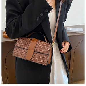 Close-up of brown woven texture and smooth leather on a vintage shoulder bag detail