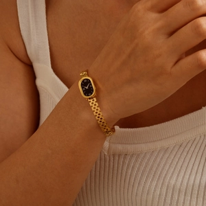 Close-up of vintage gold watch bracelet with black oval dial and Roman numerals on wrist