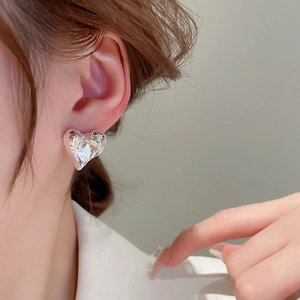 Détail de boucles d'oreilles cœur argentées avec texture lave sur l'oreille