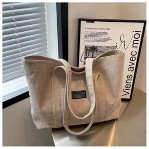 Detail shot of beige canvas tote bag with 'FASHION' label and urban lifestyle aesthetic
