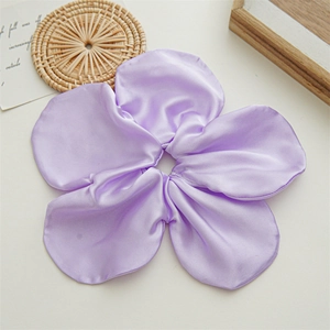 Macro detail of large purple satin flower scrunchie with soft silk texture for hair