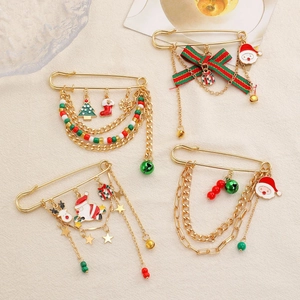 Festive Christmas paperclip brooches with Santa, snowflake, and tree charms on beige cloth