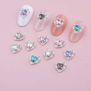 Detail of heart-shaped nail art crystals with silver alloy frames on a pink background